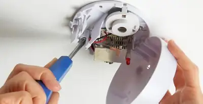 Certified technician wiring smoke detector during installation in Palm Springs, CA